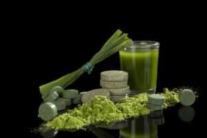 Alternative natural medicine. Green dietary supplements. Spirulina, chlorella and wheat grass isolated on black background. Green superfood, detox.